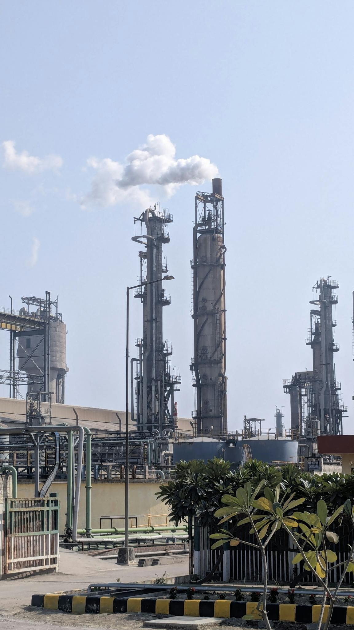 A detailed view of a chemical plant's tall chimneys and industrial structures against a clear sky.